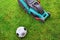Soccer ball and lawn mower on the grass. View from above. Grass care