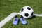 Soccer ball and pair of soccer football sports shoes cleats on green artificial turf football field with white lines