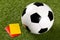 Soccer ball with referee yellow and red cards on grass background - penalty, foul or sports concept