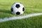 Soccer ball sits on grass field with white stripe