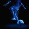 Soccer blue player kicker on black background kicking football with dramatic lighting.
