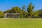 Soccer field and white goal with trees and blue sky background
