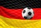 Soccer football ball and flag of Germany with goal at soccer net