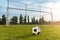 Soccer/football ball in front of empty goal at sunset