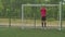 Soccer goalie practicing to defend football goal on pitch outdoors
