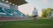 A soccer player in gear on a soccer field near the stands receives a pass and runs away with a soccer ball in slow