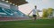 A soccer player in gear on a soccer field near the stands receives a pass and runs away with a soccer ball in slow