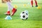 Soccer player is jogging with blurry cone markers and football on  artificial turf