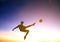 Soccer player kicks ball with sunset background