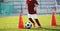 Soccer slalom cone drill. Boy in red soccer jersey shirt running with ball between cones