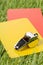 Soccer sports referee yellow and red cards with chrome whistle on grass background selective focus