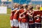 Soccer team huddling. Kids in red sportswear standing together and listening to coach