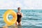 Social distance and virus protection. A woman in a bathing suit removes a medical mask and poses with an inflatable circle while