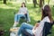 Social distancing. Girls Friends chilling among trees at picnic with social distance in summer park. Leisure activity together in