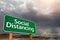 Social Distancing Green Road Sign Against Ominous Stormy Cloudy Sky