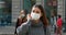Social Distancing. Young woman in city street wearing surgical mask waiting public transport respecting social distancing