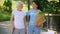 Social volunteer holding grocery bag supporting aged woman with walking stick