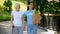 Social volunteer holding grocery bag supporting aged woman with walking stick