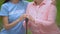 Social volunteer stroking old patient hand on walking stick, hospice support