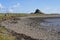 Socially distanced people walking on the shoreline to Lindisfarne Castle