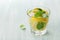 Soda water or mineral water with limes, lemons, ice and mint leaves on light blue background
