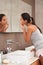 Soft, blemish-free skin. A beautiful young woman looking at her face in her bathroom mirror.