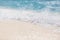 Soft blue ocean wave on clean sandy beach. Summer beach closeup template, waves splashing on white sand