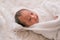 Soft blurred image of Asian newborn baby cover by white cloth on white bed and smile to show emotion of relax and happy