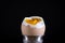 Soft boiled brown egg in eggcup on black background