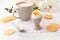 Soft-boiled egg with liquide orange yolk in ceramic egg cup, cup of coffee and thin crispy corn chips on background of