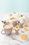 Soft-boiled eggs with liquide orange yolk in ceramic egg cups, two cups of coffee with ceramic spoons and thin crispy