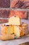 Soft cheese with cut off slice creamy texture, orange rind with mold, French, German,red pepper corns, close up, brick wall