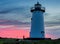 Soft clouds reflect morning sunrise colors behind Edgartown lighthouse in Martha`s Vineyard