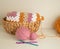 Soft coloured woolen balls with granny square blanket and crochet hook in basket