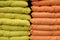 Soft comfortable orange and yellow pillows are stacked on shelf. Pillows background. Household items for home bedroom bed