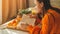 Soft cozy photo of woman in warm orange sweater on the bed with cup of tea and fruit. Girl sitting on the bed with old books.