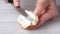 Soft cream cheese butter is spread with a knife on slices of French baguette. cooking of a delicious healthy sandwich