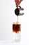 Soft drink based on coffee and mineral water. Coffee is poured into ice water. A thirst-quenching drink. Vertical photo