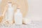 Soft elegant bathroom decor of white cosmetics bottles with comb, flowers on white wood board, mock up, copy space.
