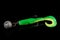 Soft fishing bait, green plastic grub, with double hook and lead sinker, isolated on black