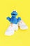 Soft fluffy children`s toy cookie monster in white shoes sneakers on a yellow background