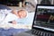 The Soft focus on baby .The parents father Stock trader trading stock on his laptop while his newborn infant baby sleep on the bed