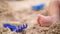 Soft focus, A close-up of tiny, little baby foot on on a sand background, there are toys nearby