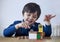 Soft focus kid with smiling face putting 50 pence on money box, Selective focus little boy making stack and poingitn finger to