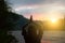 Soft focused photo. Girl is doing yoga in mountains. Wanderlust and freedom. Beautiful sunset. Woman in harmony on the river bank