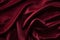 Soft folds of a smooth deep red burgundy vinous satin velvet fabric with shadows and highlights background