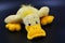 Soft funny toy, curly yellow duck located on a black background.