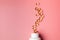 Soft gels pills with Omega-3 oil spilling out of pill bottle close-up isolated on a pink background