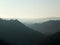 Soft hillside tree covered valley landscape blurred by fog at sunrise glowing a with the tops of hills showing though the mist