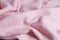 Soft knitted fabric made of cashmere with large folds, a detail of clothes. pink fabric texture